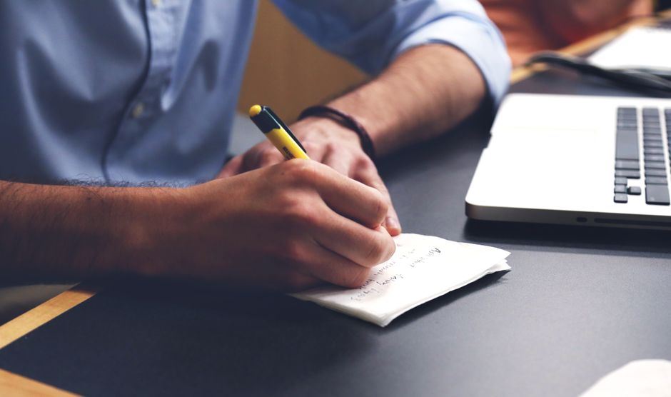 Writing notes beside a laptop
